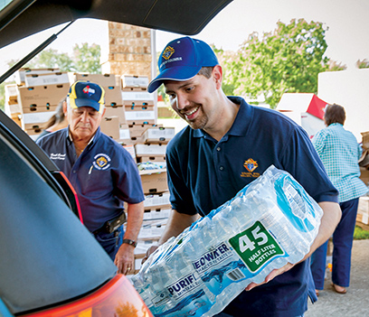Knights load packs of drinking water to a van during disaster relief efforts 