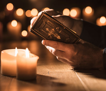 An individual reading a Bible with lit candles