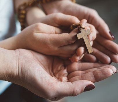 A family praying together while holding a rosary