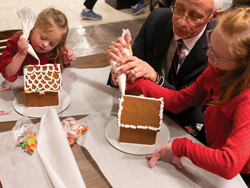Jeff McGarrity, a member of St. Thomas More Council 10205 in Centennial, helps his daughters decorate gingerbread houses at the council’s Christmas party at St. Thomas More Parish on Dec. 10. (Photo by Rachel Woolf)