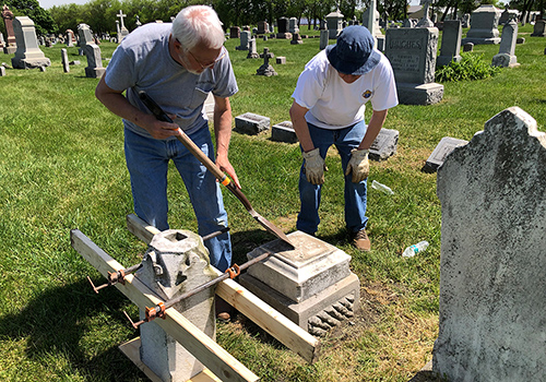 Past Grand Knight Dan Pellum (left) and Larry Swinyer of Twin City Council 891 in Champaign, Ill., repair a headstone in St. Mary’s Cemetery. Members of Council 891 and other local councils have been tackling maintenance projects at the cemetery since 2019.