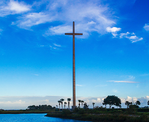 A large cross statue next to a lake