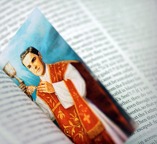 a Michael McGivney bookmark resting in an open page of a book