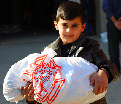 An Iraqi refugee child holding a bag of food with a Knights of Columbus logo