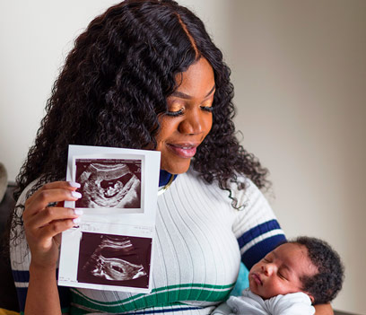 A young mother holds her ultrasound from the Knights of Columbus and her beautiful newborn baby