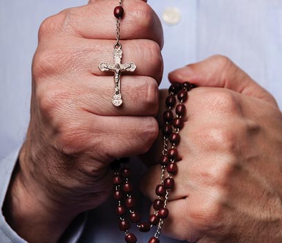 A person holding a rosary and praying