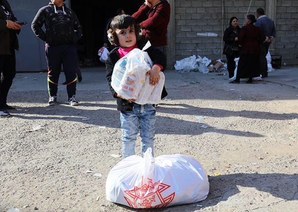 A boy holding a bag of food donations from Knights of Columbus